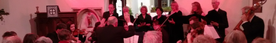 A choir and orchestra performing in the church under warm lighting