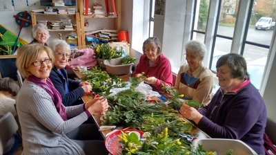 Members of the flower team arranging greenery around a table in the hall